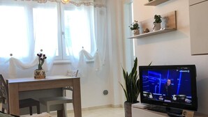 A modern living room with a sofa, a dining table, and a TV displaying a news channel. - in the Heart of the City of Bari (Bari)