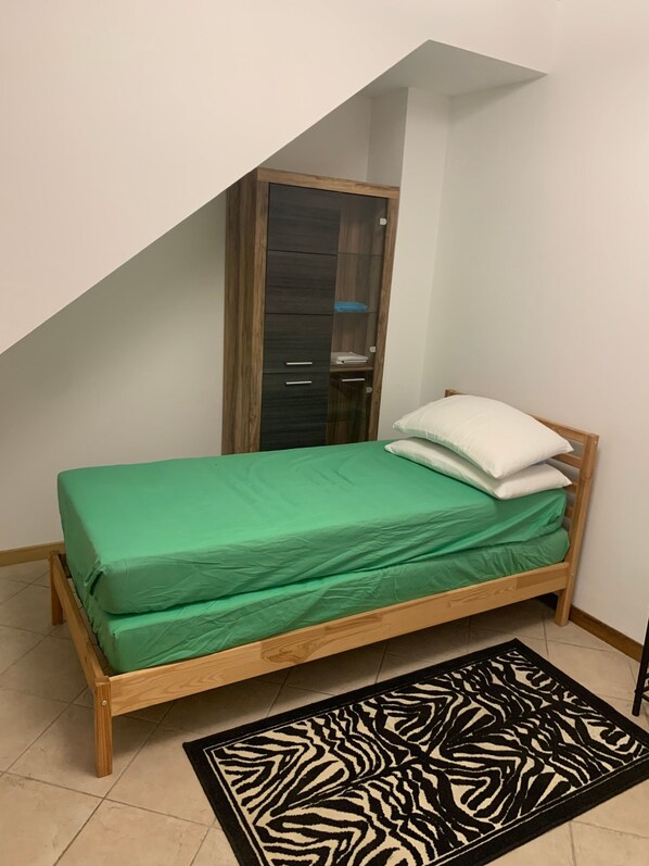 A small bedroom with a single bed, a wardrobe, and a zebra-patterned rug.