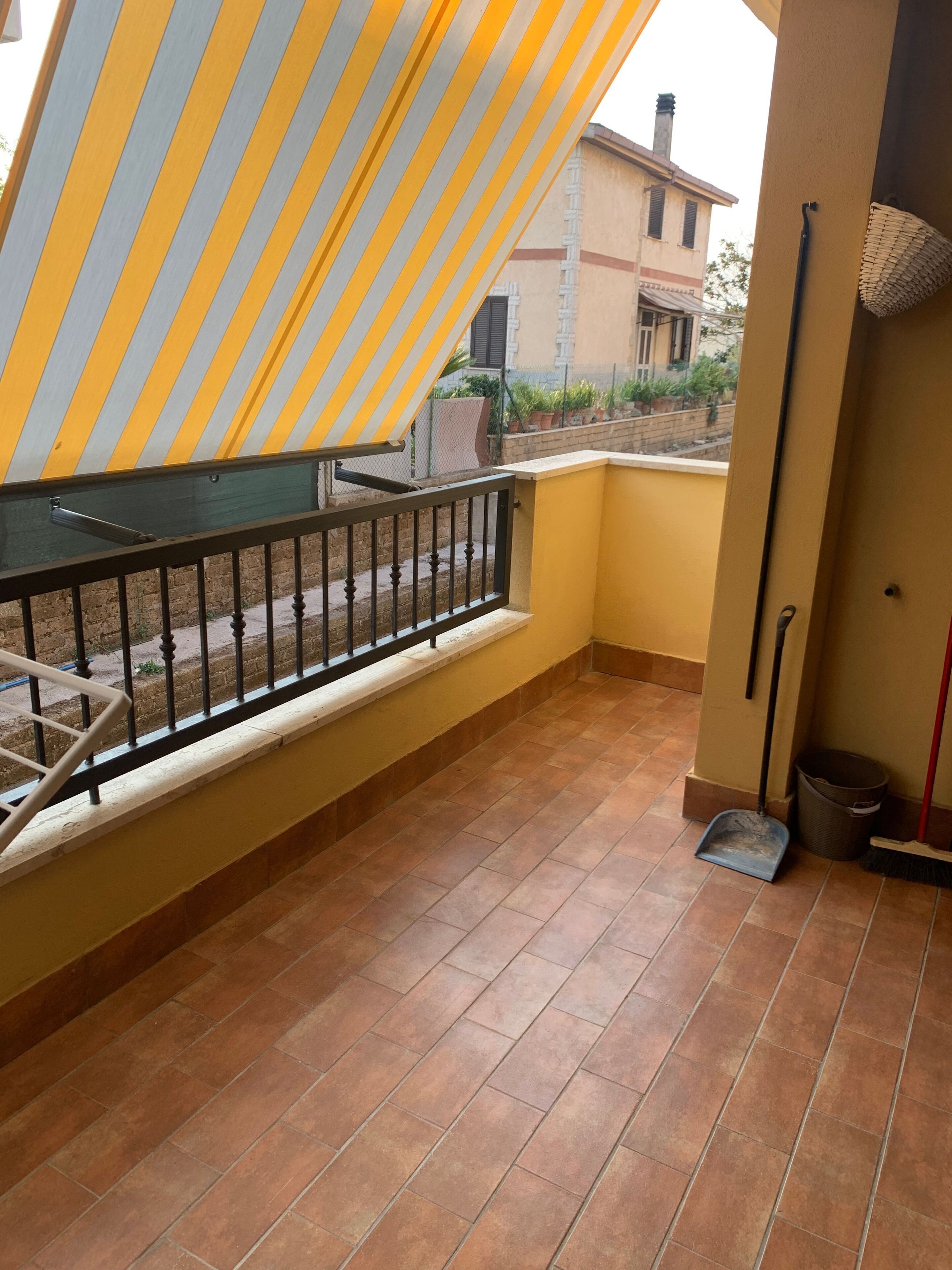 A balcony with tiled flooring, a metal railing, and a view of a building in the background.