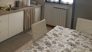 Ett kompakt kök med en matplats, utrustat med ett element, ett fönster med gardiner och en hängande lampa.