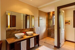 A modern bathroom with a large mirror, two sinks, and a glass shower enclosure.