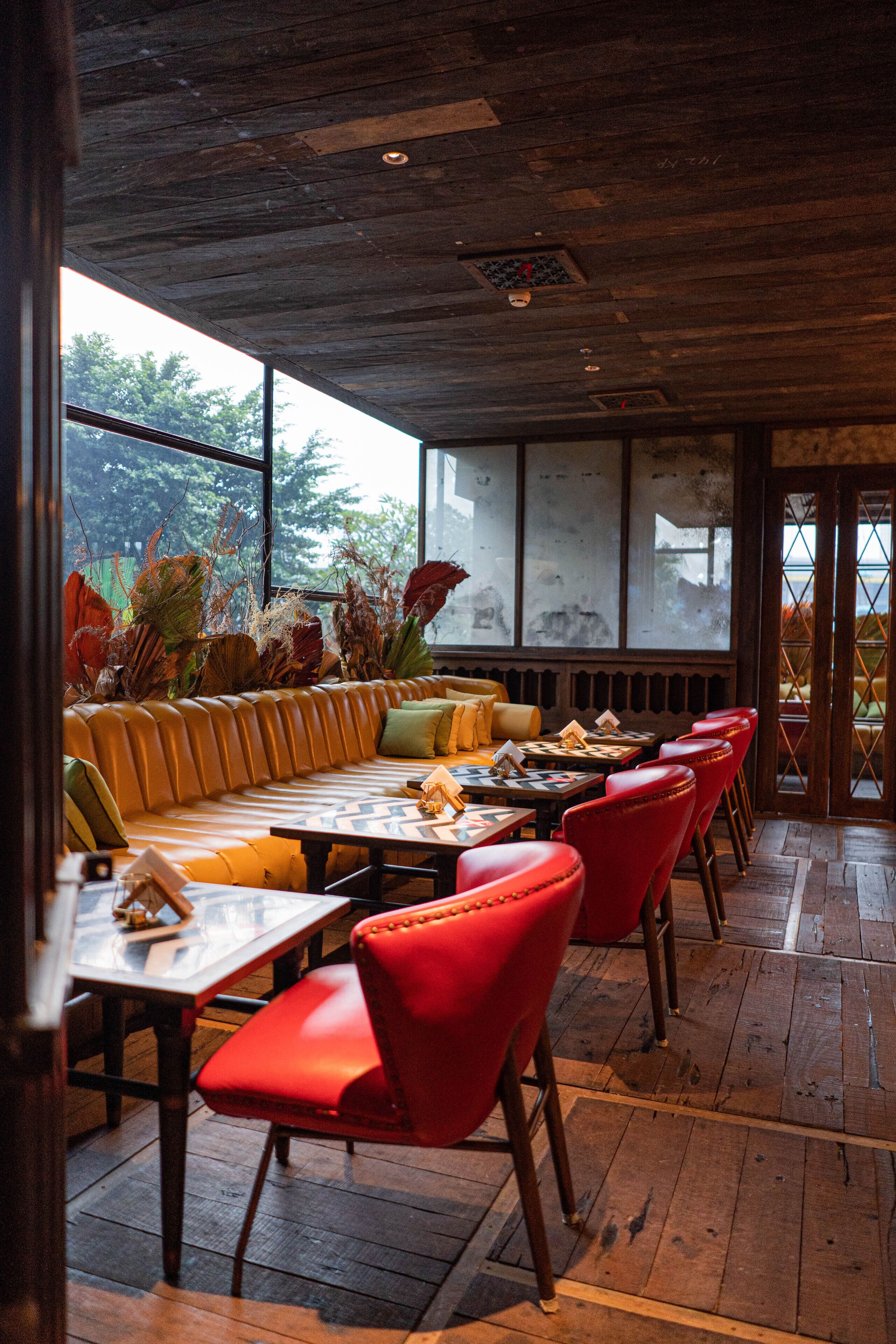 A restaurant with a wooden ceiling, a yellow sofa, red chairs, and a table with a chessboard.