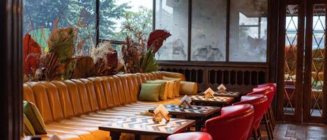 A restaurant with a wooden ceiling, a yellow sofa, red chairs, and a table with a chessboard.