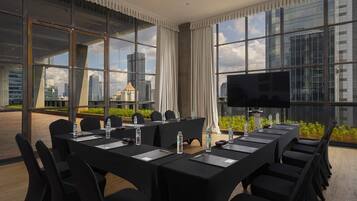A conference room with a city view, large windows, and a flat-screen TV.