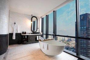 A modern bathroom with a freestanding bathtub, a large mirror, and a view of a cityscape through large windows. - The Orient Jakarta, a Royal Hideaway Hotel (Jakarta)