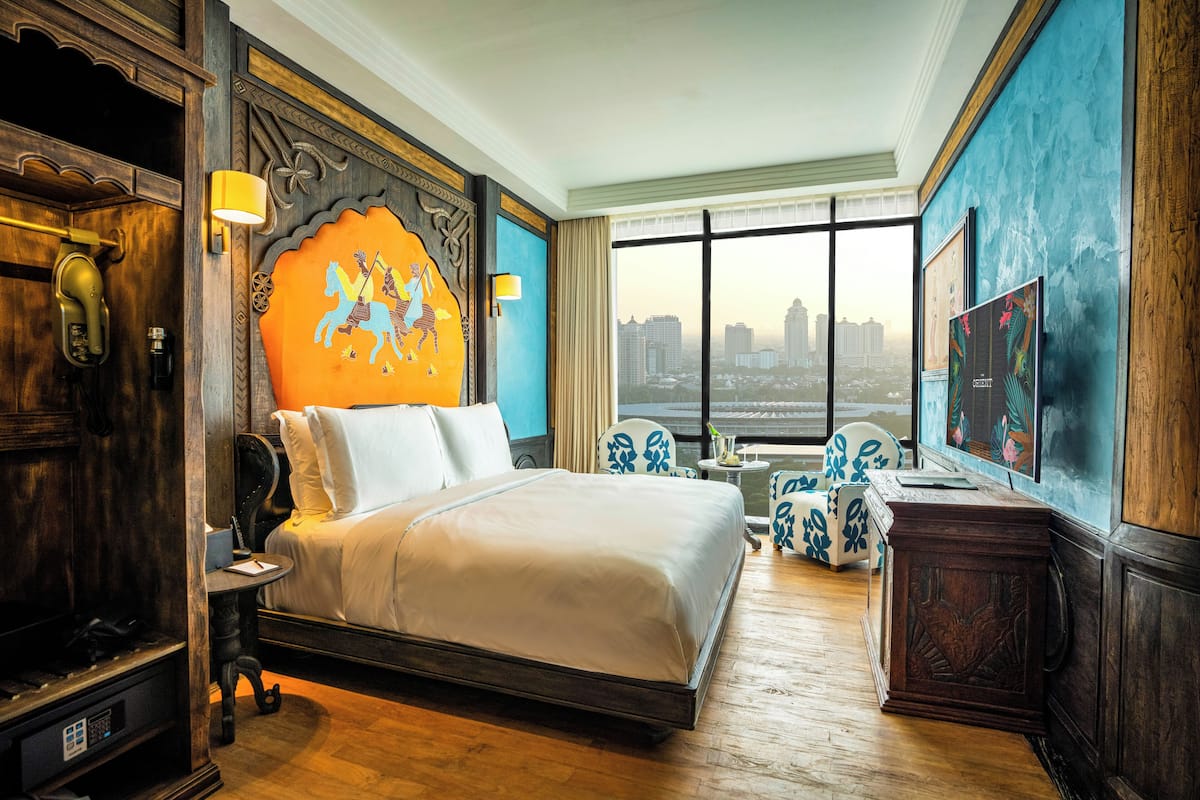 Een hotelkamer met een groot bed, uitzicht over de stad en een decoratieve wand.