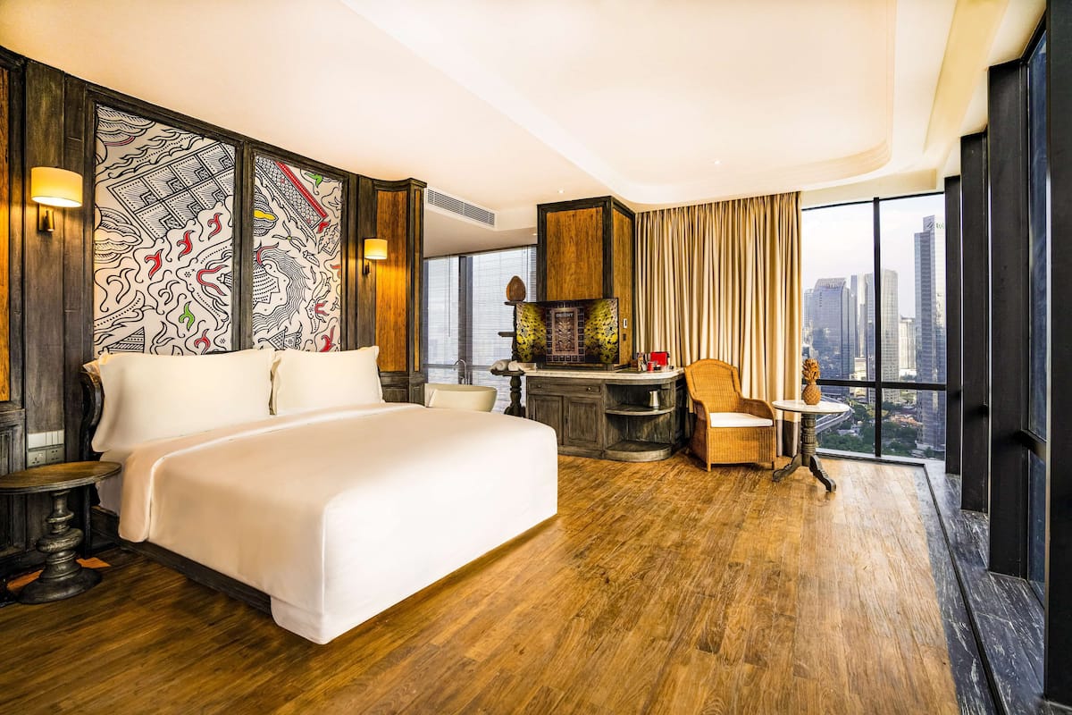 Een hotelkamer met een groot bed, een zithoek en uitzicht op de skyline.