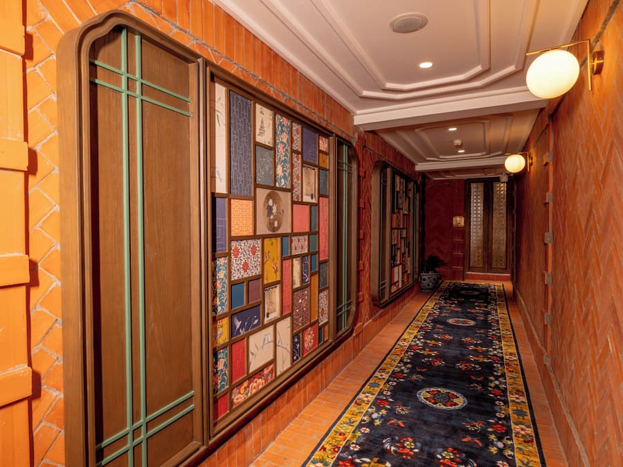 Un pasillo con alfombra estampada, paredes de madera y suelo de baldosas.