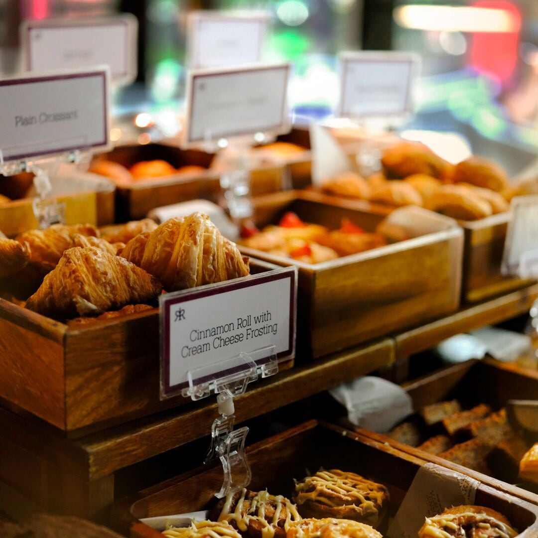 A bakery display with various pastries and a sign indicating a cinnamon roll with cream cheese frosting.