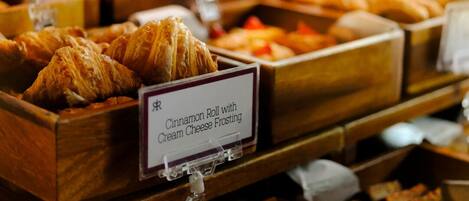 A bakery display with various pastries and a sign indicating a cinnamon roll with cream cheese frosting.