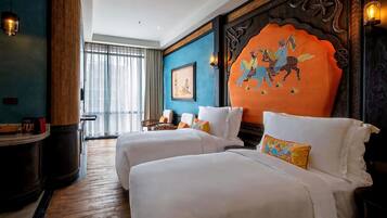 A hotel room with two beds, a wooden accent wall, a framed picture, and a large window with curtains.