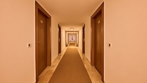 En hotelgang med flere døre, hver mærket med et nummer.