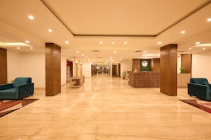 A spacious lobby with a marble floor, two reception desks, and blue armchairs. - Renest Haridwar (Haridwar)