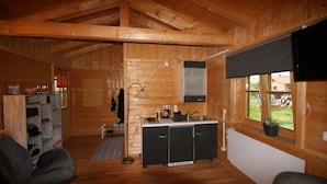 A wooden cabin interior with a kitchenette, two chairs, a lamp, and a window with a view of the outside. - Kargl's alpine hut (Bad Kohlgrub)