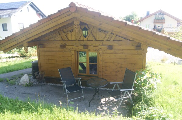 A wooden cabin with a sloped roof, a window, and two chairs and a table outside. - Kargl's alpine hut (Bad Kohlgrub)