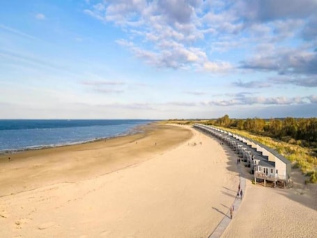 A beach with a long row of beach huts along the shore.