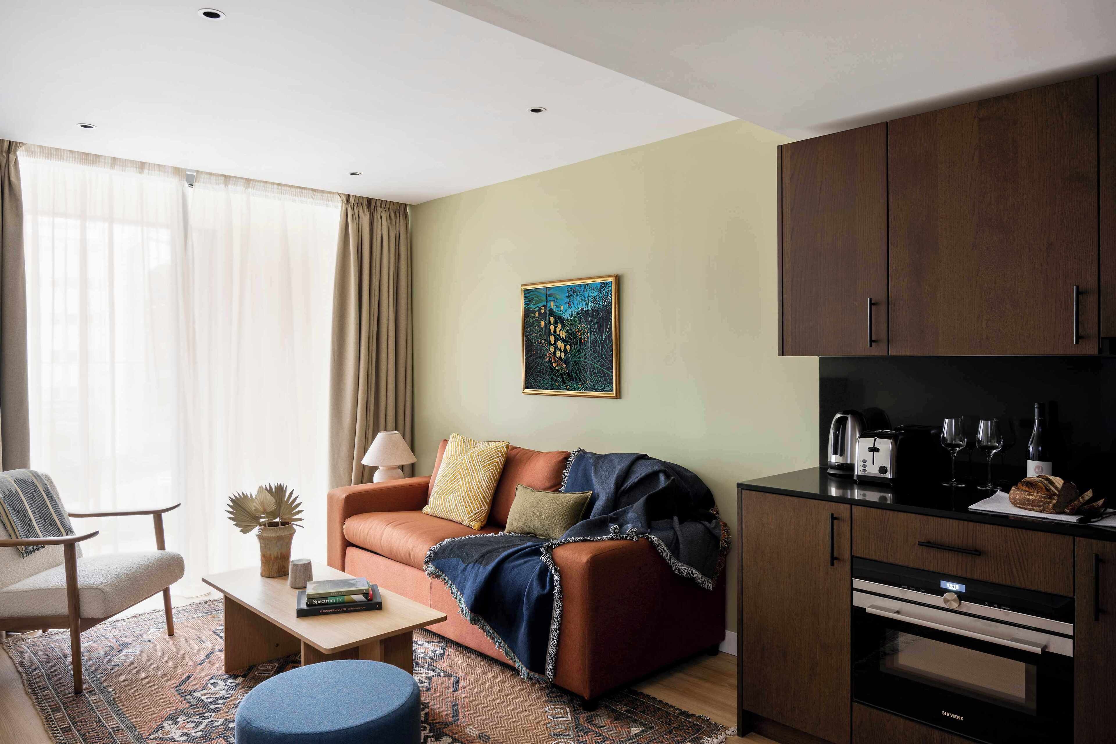 Ein modernes Wohnzimmer mit Sofa, Couchtisch und einem Essbereich mit Küchenzeile.