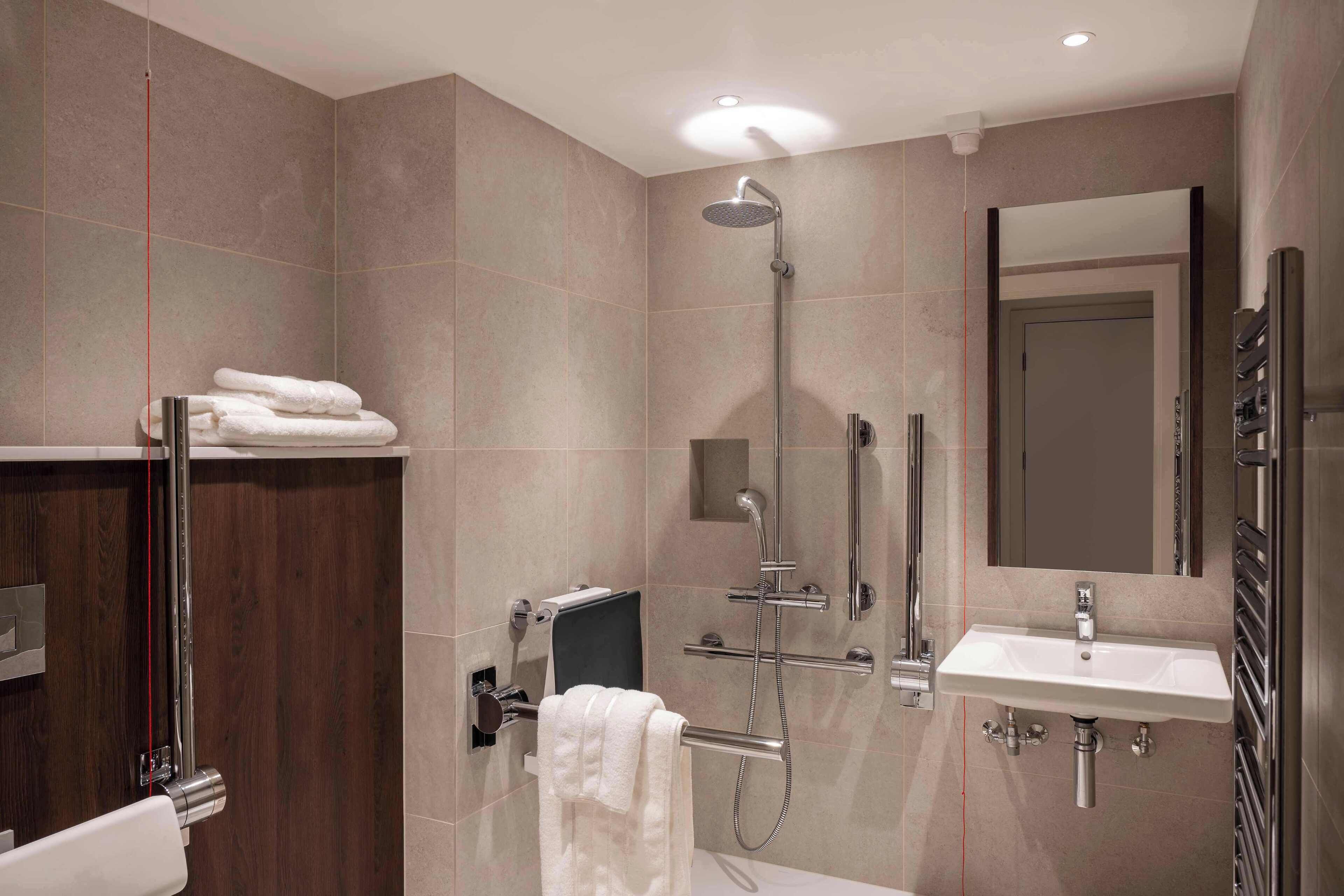 Un baño moderno con cabina de ducha, tocador con lavabo y espejo.