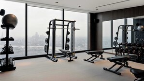 A high-rise gym with panoramic city views, equipped with various weightlifting stations and cardio machines. - Cove Landmark Pinnacle (London)