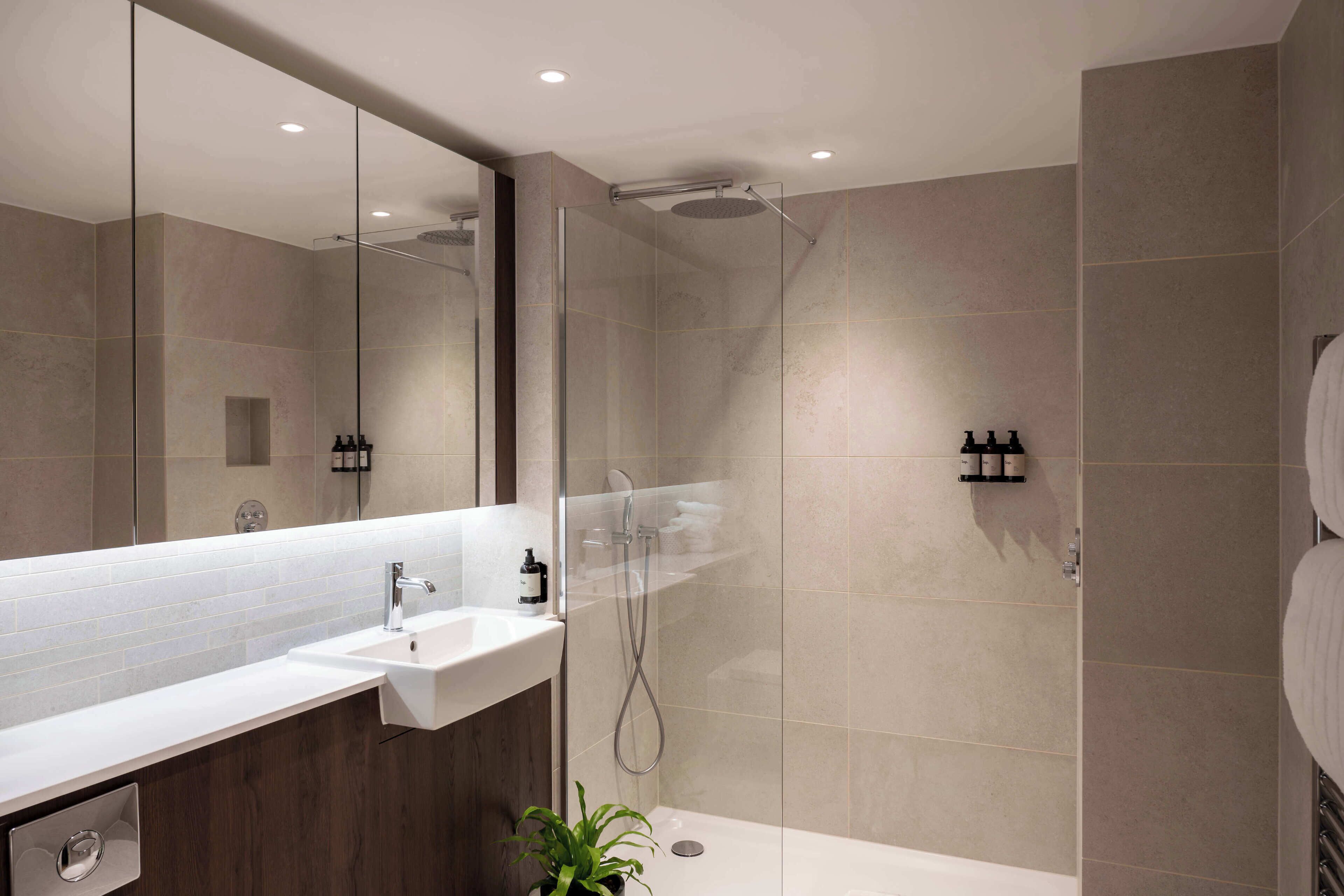 A modern bathroom with a glass-enclosed shower, a sink, and a mirror.