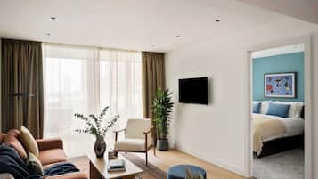 Een moderne woonkamer met een bank, fauteuil, salontafel en een potplant.