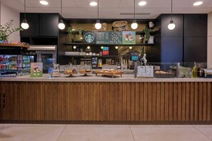 A Starbucks coffee shop counter with a wooden panel design, a menu board, and various coffee-making equipment. - Cove Landmark Pinnacle (London)