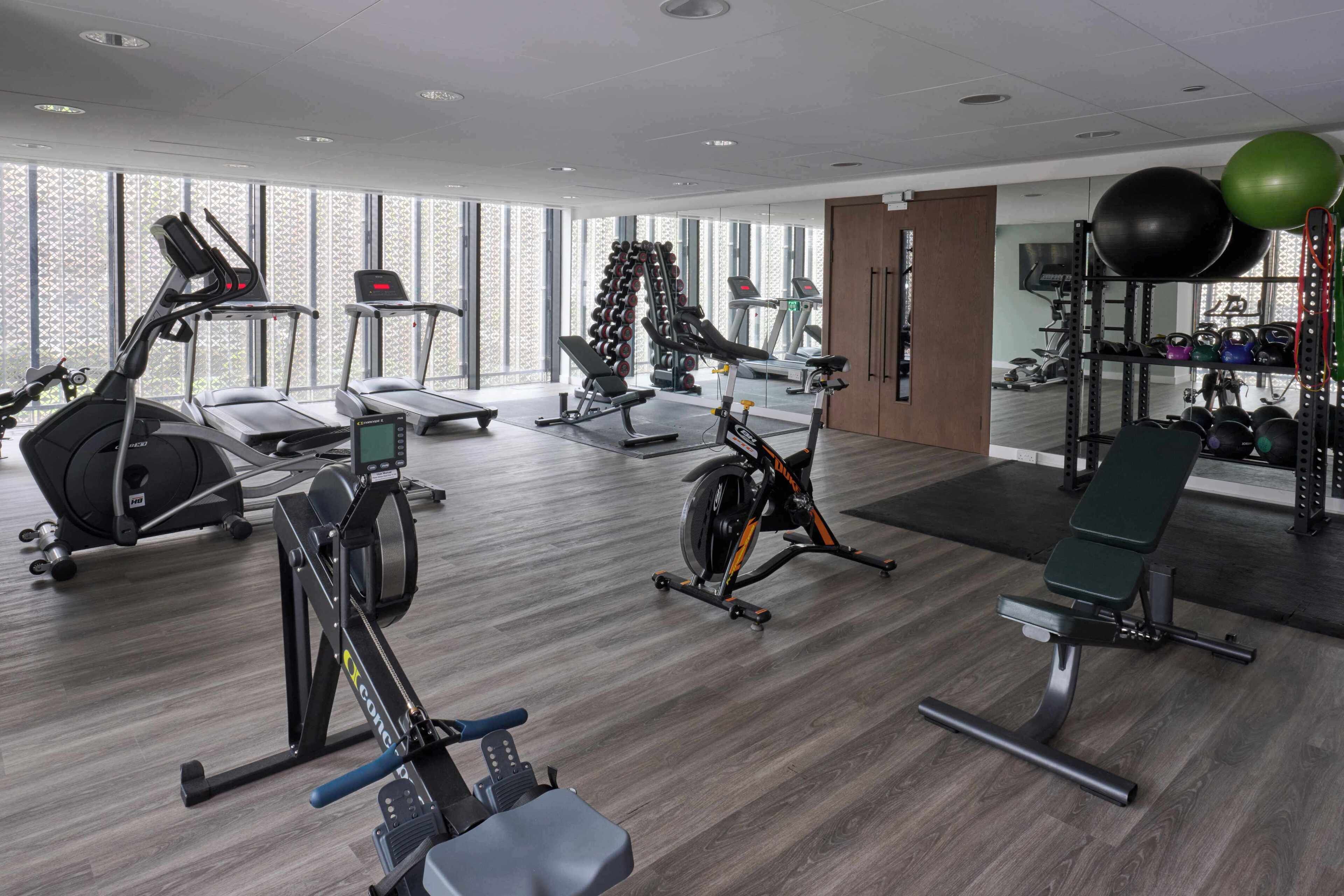 A modern gym with cardio machines, weightlifting equipment, and exercise balls.