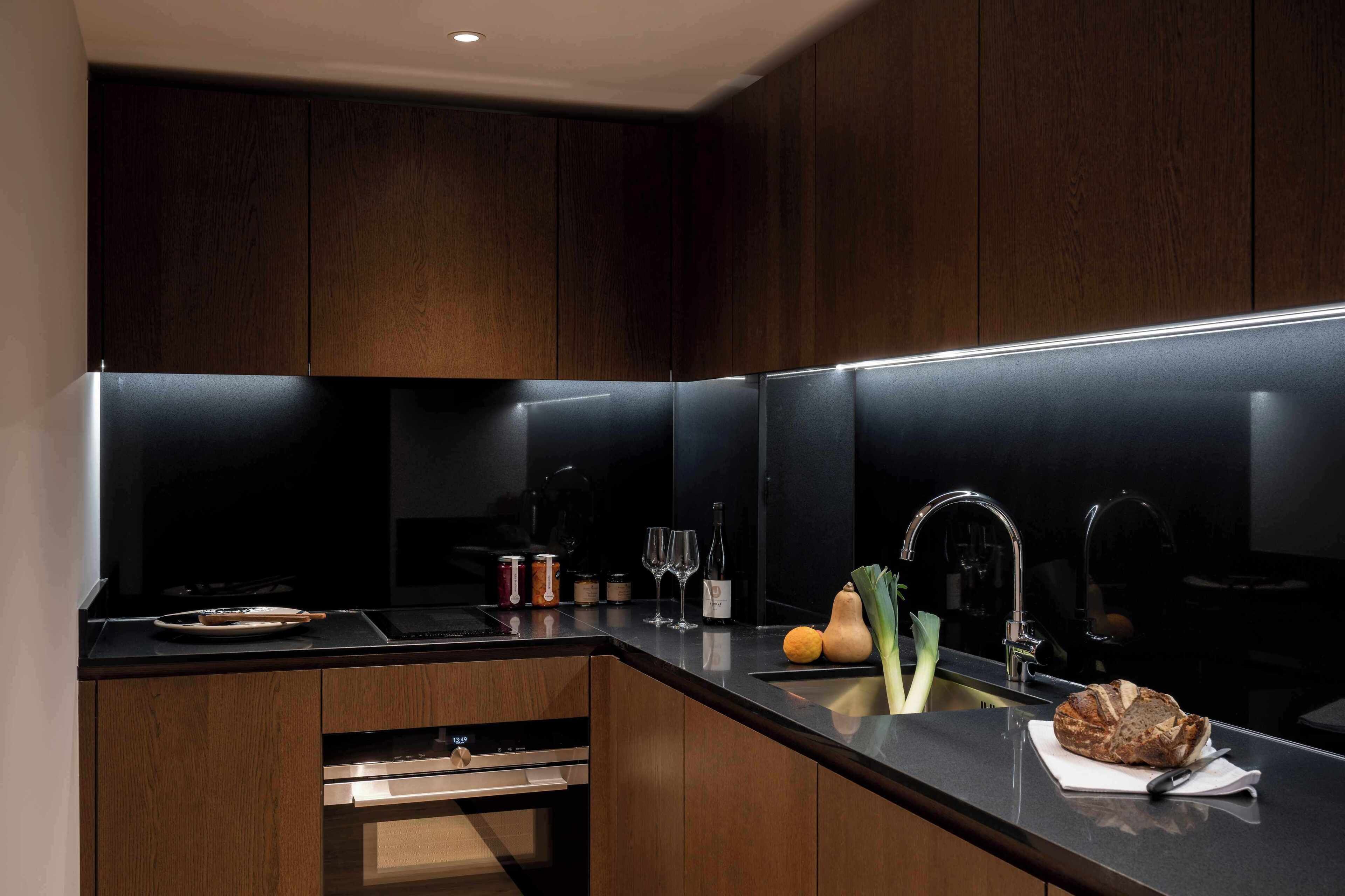 A modern kitchen with dark wood cabinets, a black countertop, and stainless steel appliances.