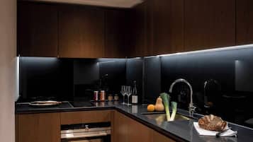 A modern kitchen with dark wood cabinets, a black countertop, and stainless steel appliances.
