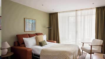 Une chambre d’hôtel avec un lit, un canapé, une chaise, une lampe et un tableau au mur.