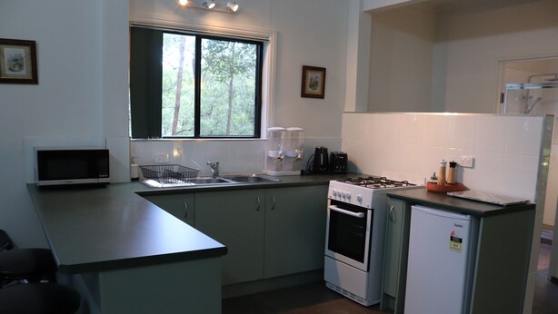 A compact kitchen with a microwave, stove, refrigerator, and a window with curtains. - Green Trees, Secluded, self contained chalet. (landsborough)