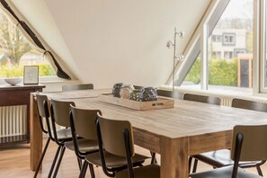 A dining area with a wooden table and chairs, a tray with decorative items, and a view of the outside through large windows.