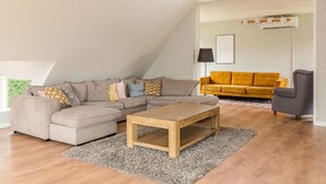Una sala moderna con un sofá modular, una mesa de centro de madera y un sofá amarillo.