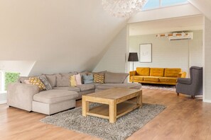 Una sala moderna con un sofá modular, una mesa de centro de madera y un sofá amarillo.