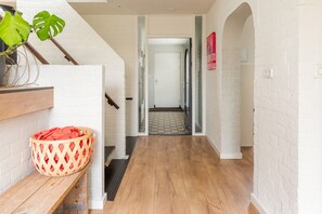 A hallway with a wooden floor, a red woven basket, and a plant.