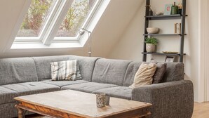 Een moderne woonkamer met een hoekbank, een houten salontafel en een ingebouwde boekenkast.