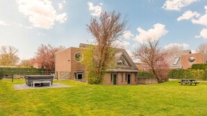 Een woongebouw met een bakstenen gevel, een rond raam en een kleine tuin met een picknicktafel.