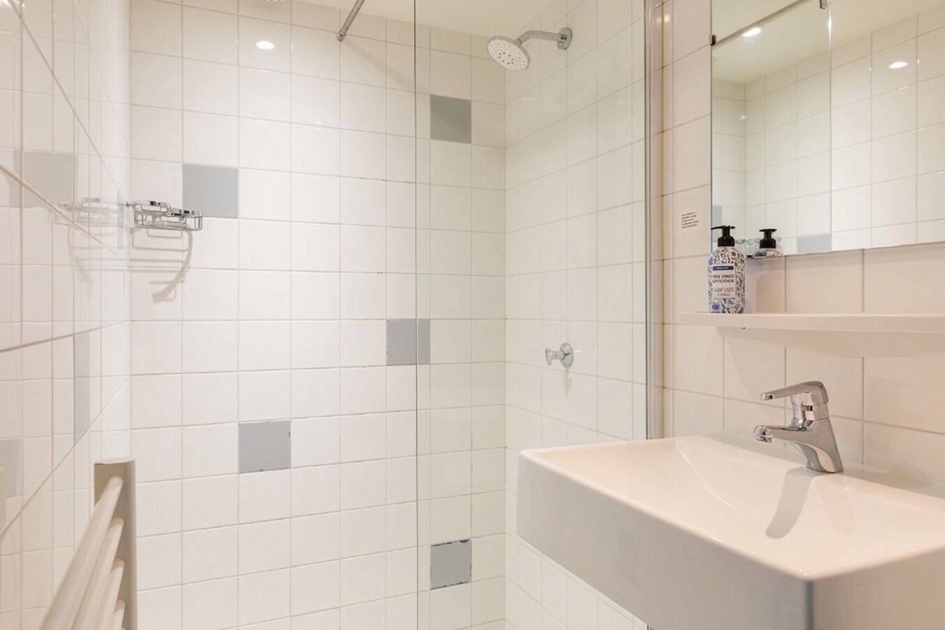 Une salle de bain moderne équipée d’une douche, d’un lavabo et d’un miroir.