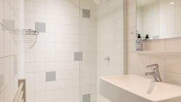 Une salle de bain moderne équipée d’une douche, d’un lavabo et d’un miroir.