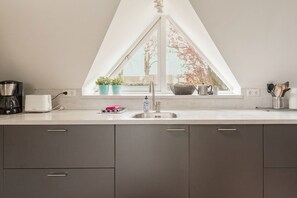 Een moderne keuken met een raam, een koffiezetapparaat, een broodrooster en een spoelbak.