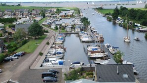 Un puerto deportivo con barcos amarrados a lo largo del agua, una carretera que conduce al puerto y vistas del río.