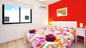 A bedroom with a bed, a nightstand, a window, and a red wall. - Remarkable 2-bed House in Chayofa With Pool (Arona)