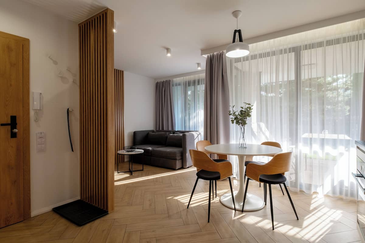 Een moderne woonkamer met een bank, een eettafel met stoelen en een keuken met een fornuis.