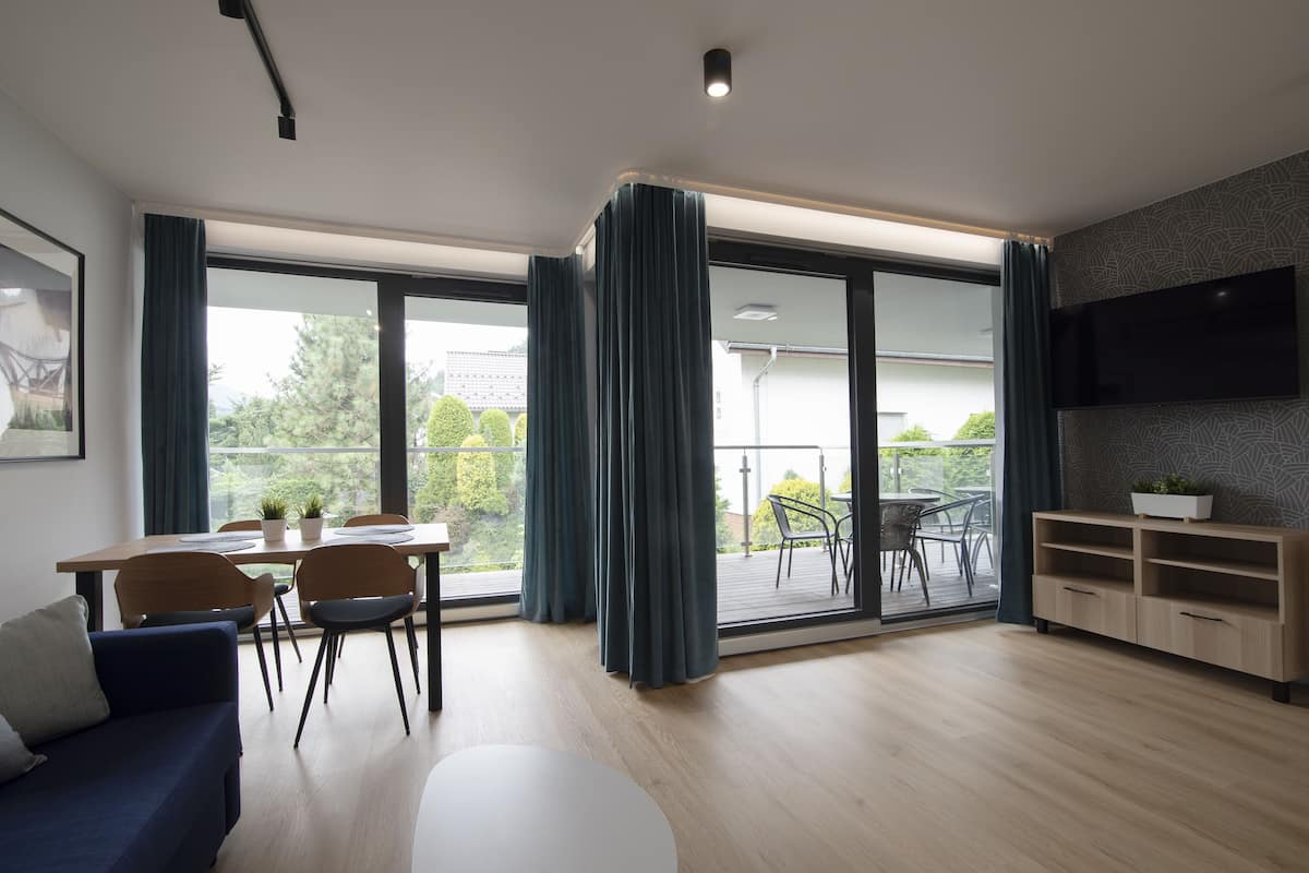 Een moderne woonkamer met een bank, eettafel, stoelen en een televisie.