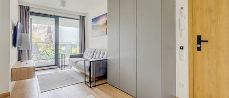 Una sala de estar moderna con un sofá gris, un televisor y un ventanal con vistas al exterior.