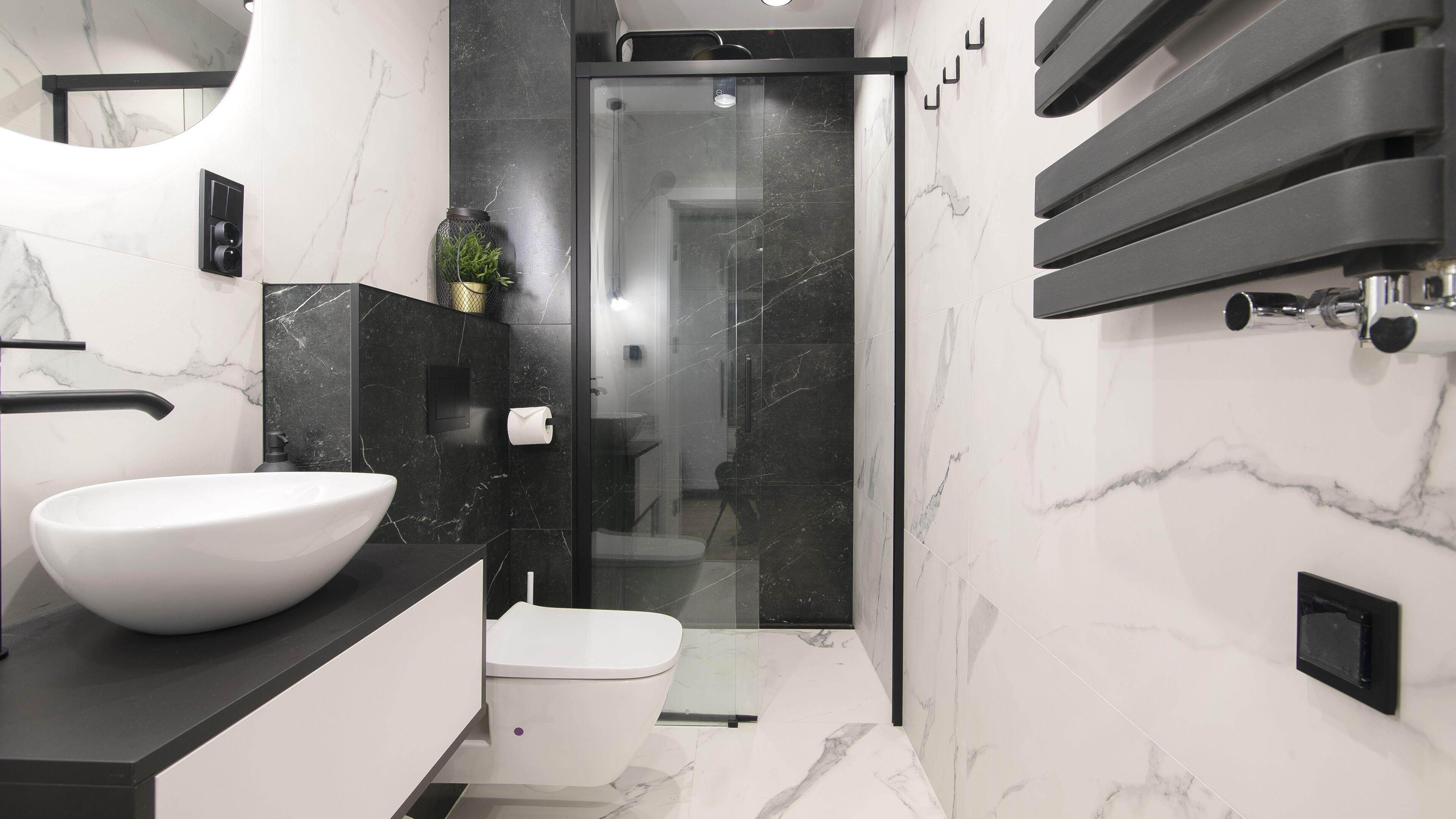 Een moderne badkamer met een groot wit wastafelmeubel, een toilet en een douche met glazen wanden.