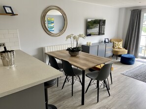 Un comedor moderno con una mesa de madera, sillas negras y una orquídea en maceta.