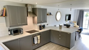 A modern kitchen with grey cabinets, a built-in microwave, and a large island with a sink.