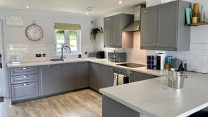 A modern kitchen with grey cabinets, a white countertop, a built-in oven, and a coffee machine.