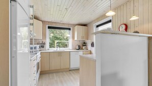 Une cuisine moderne avec des meubles en bois, un réfrigérateur blanc et une fenêtre qui laisse entrer la lumière naturelle.